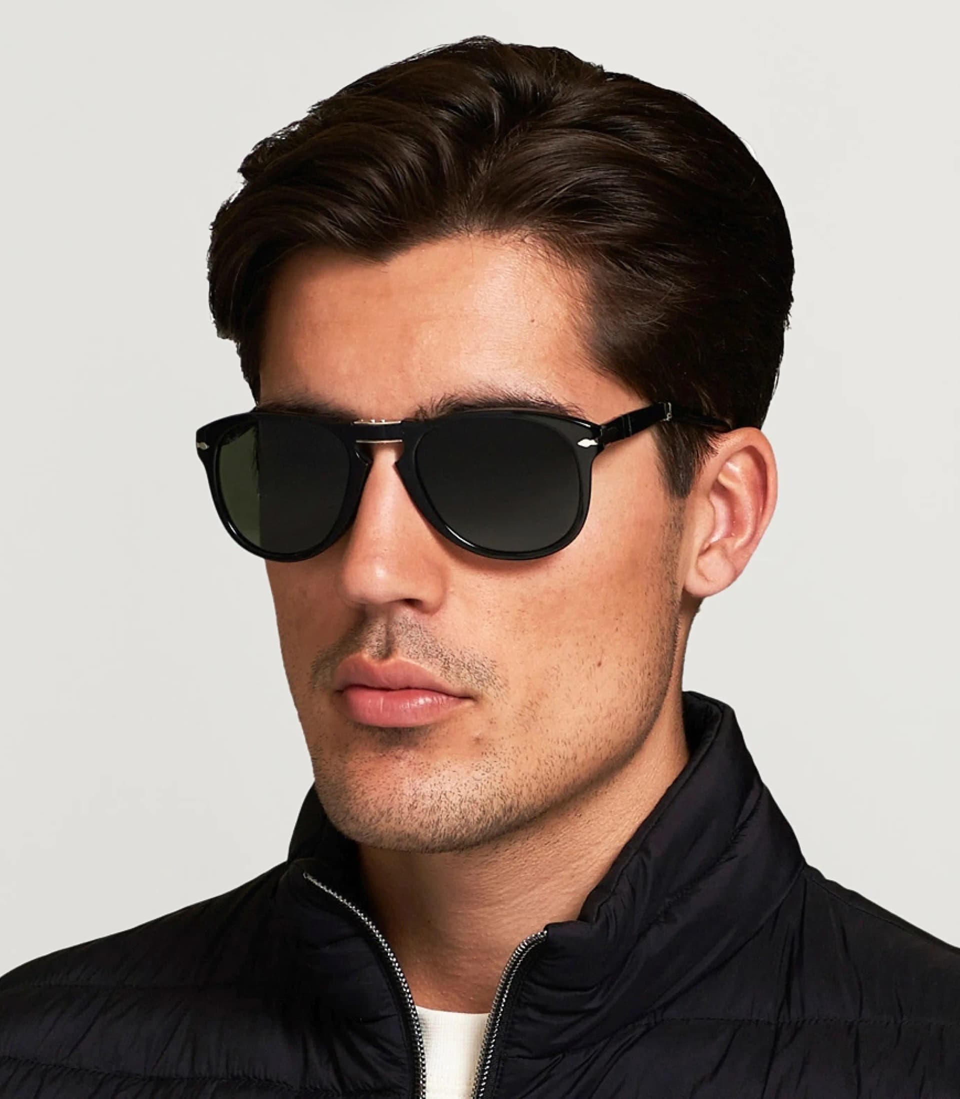 Man with dark sunglasses and gold accents looking down
